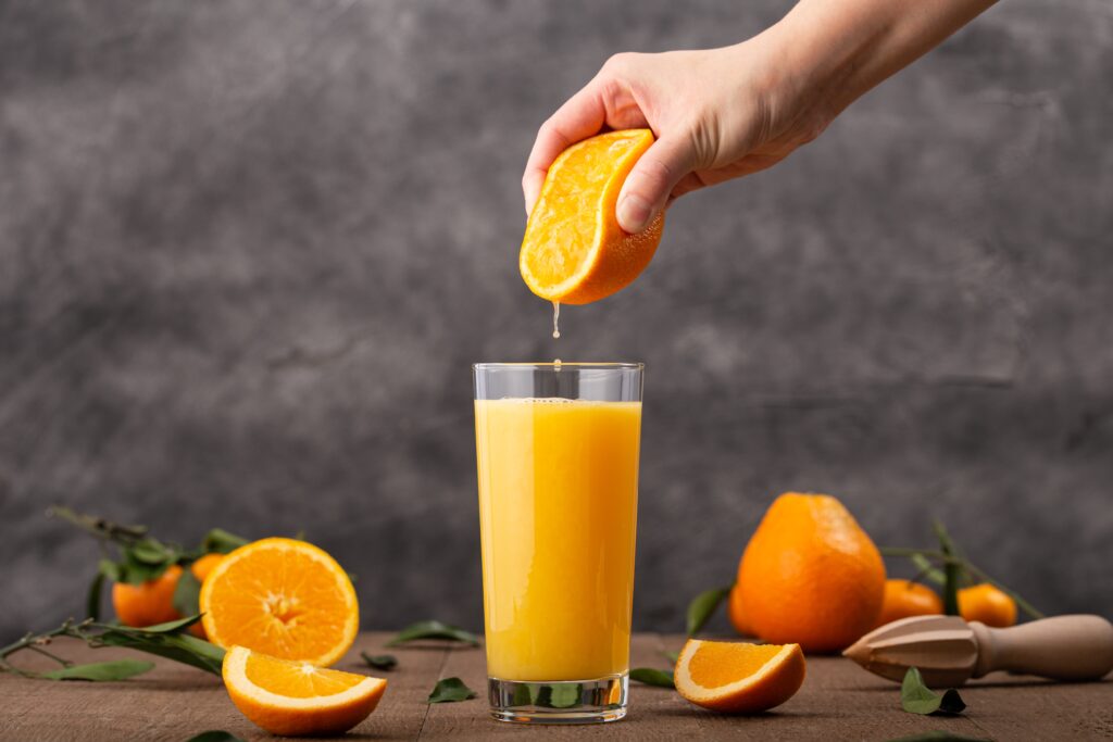 A imagem atual não possui texto alternativo. O nome do arquivo é: copo-de-suco-de-laranja-e-uma-pessoa-espremendo-uma-laranja-nele-scaled.jpg